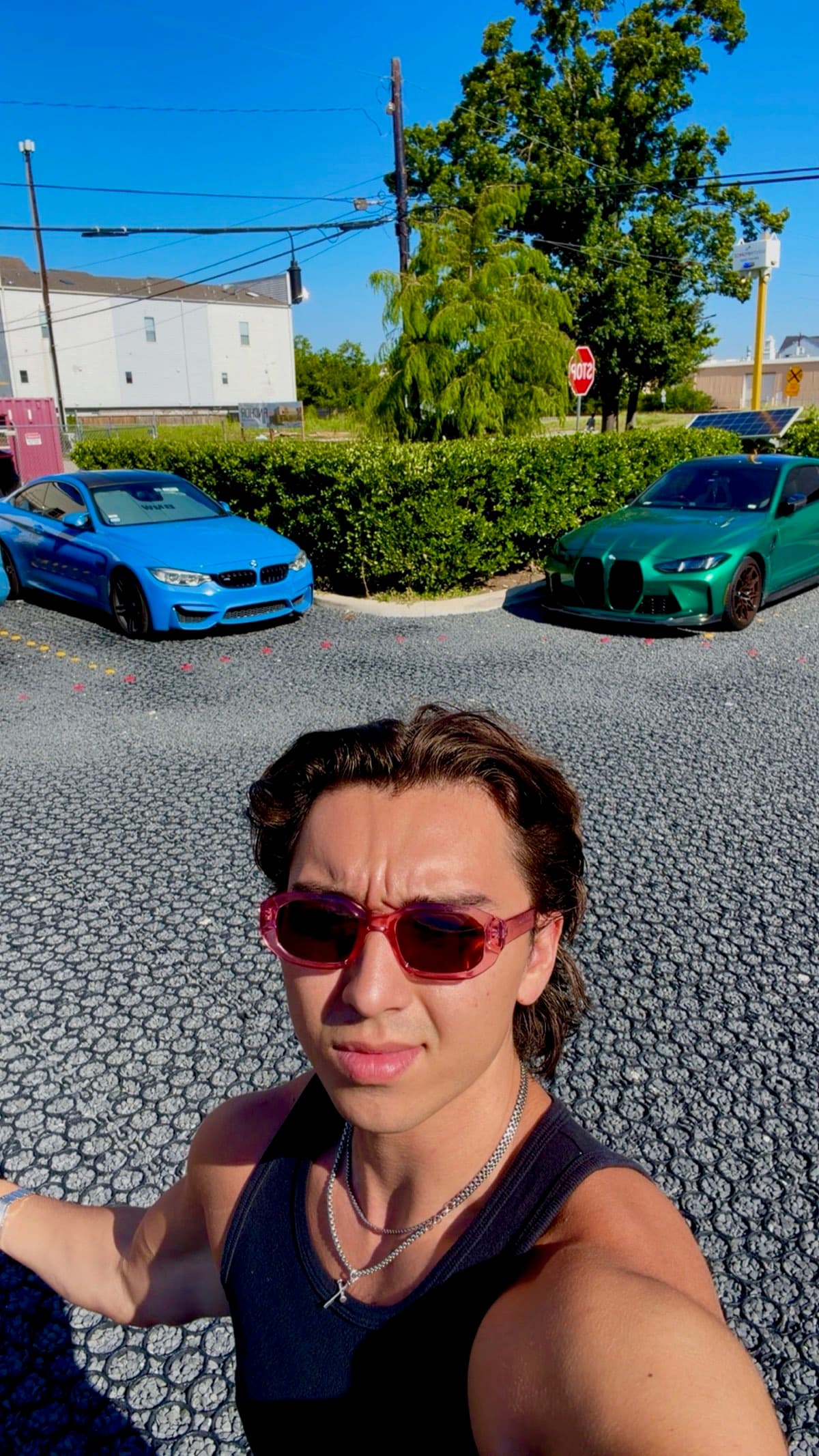 Aaron in tinted glasses, his two BMW M4s parked behind him